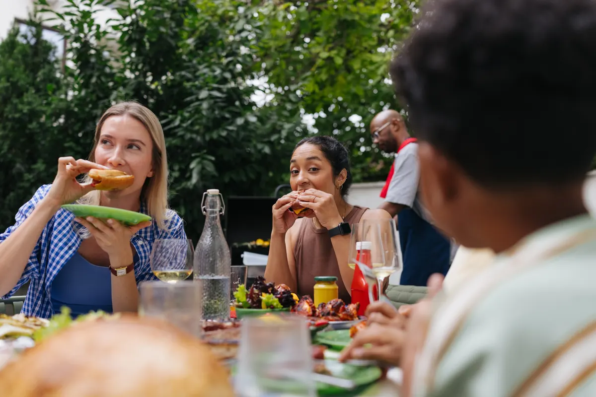 Friends tucking into burgers at a relaxed backyard barbecue
