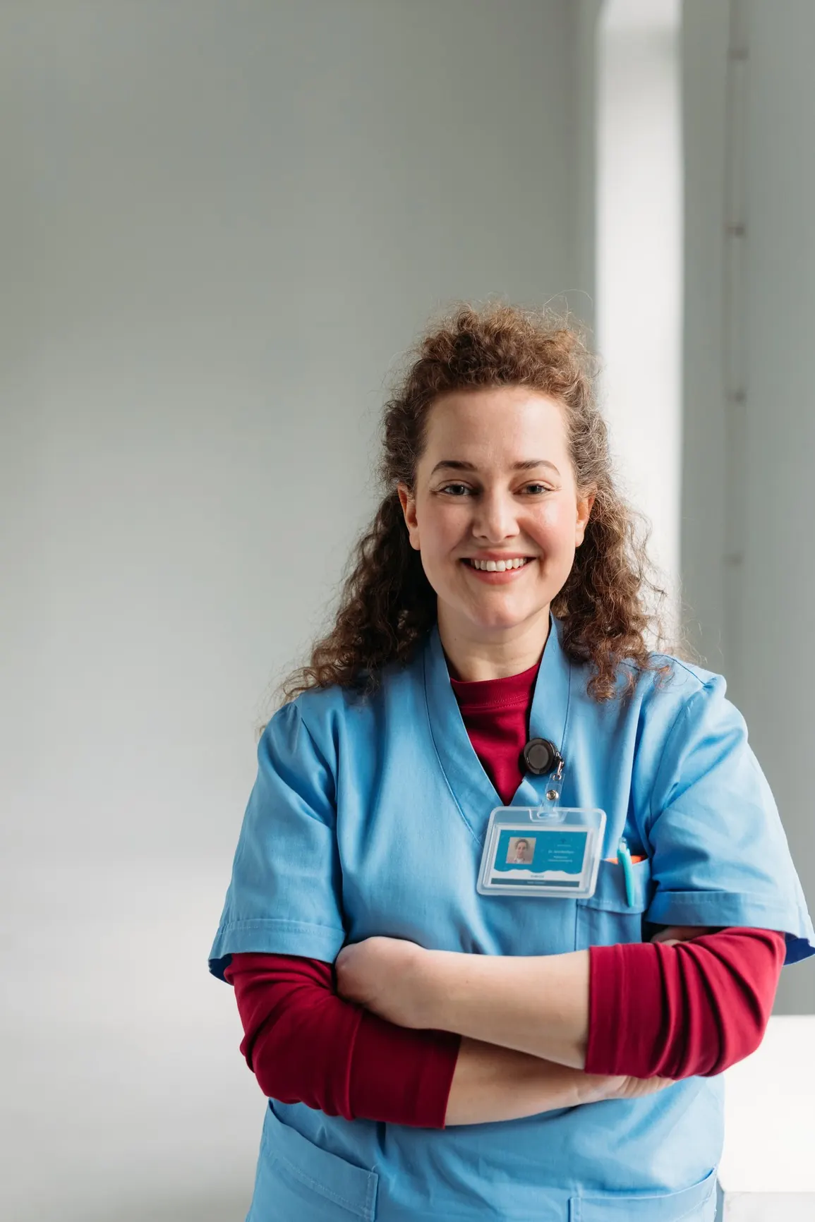 A smiling nurse in blue scrubs