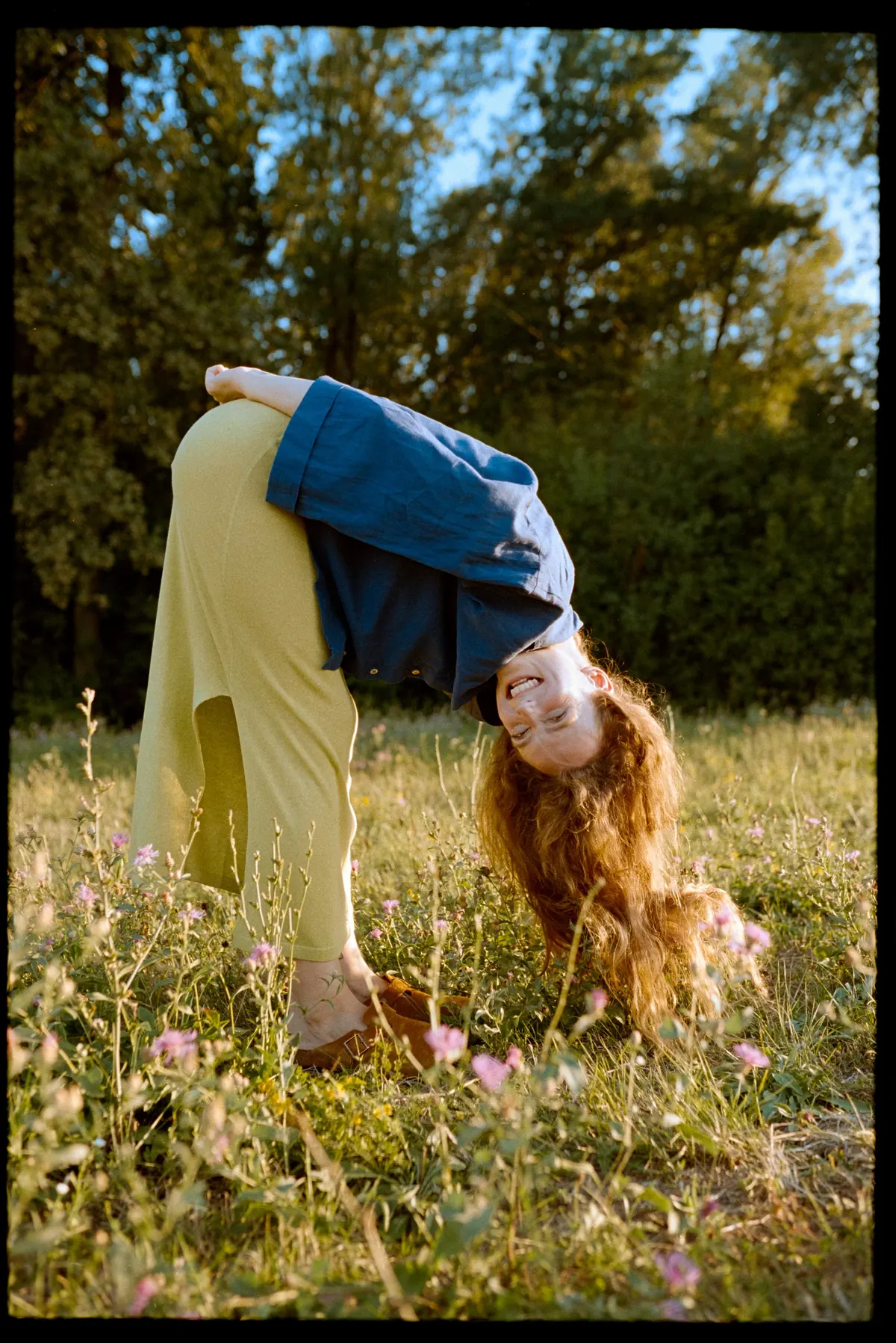 A woman stretching playfully in a sunny meadow