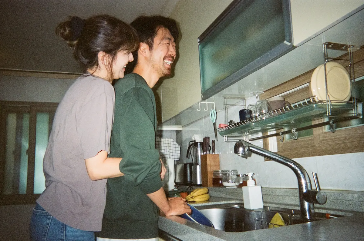 A couple laughing together at the kitchen sink