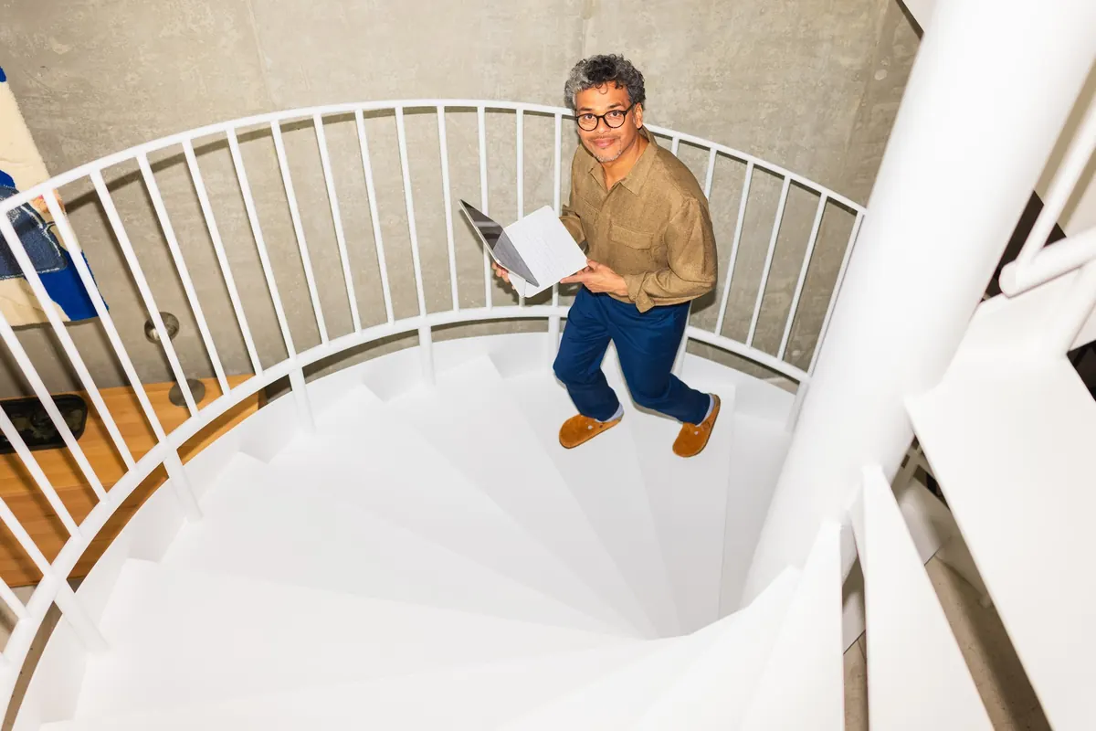 A person climbing a sunlit spiral staircase